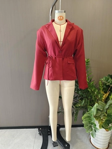 Détail du blazer rouge foncé avec col à revers, cordon de serrage à la taille et poche