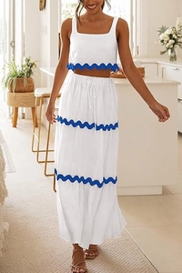 Dettaglio del bordo blu smerlato sul crop top bianco e sulla gonna a balze a vita alta