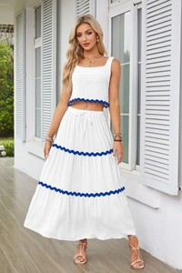 Dettaglio del bordo smerlato blu scuro sul completo top corto bianco senza maniche