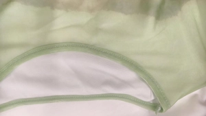 Detailed macro shot of light green mesh fabric with precise double-needle stitching