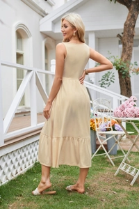 Detail of elegant beige sleeveless dress with pleated waist and layered hem in garden
