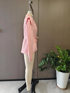 Détail du blazer rose avec épaules plissées et ceinture réglable à la taille