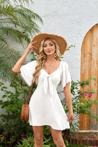 Close-up of V-neck white mini dress with bow tie detail and ruffled cap sleeves