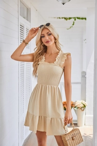Detail of apricot smocked dress with square neck, ruffled straps and pleated hemline