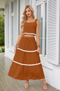 Dettaglio del set due pezzi caramello con bordo in pizzo bianco su crop top e gonna lunga