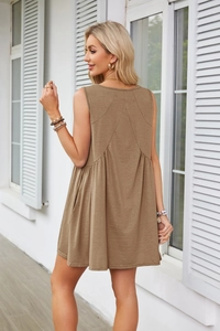 Detail of V-neck sleeveless dress featuring a ruched back seam and pleated fabric texture