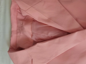 Détail du col d'un blazer rose montrant la texture sergée et la doublure soyeuse