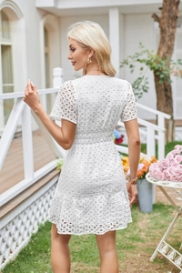 Dettaglio del pizzo bianco Broderie Anglaise e dei ricami traforati sull'abito di cotone