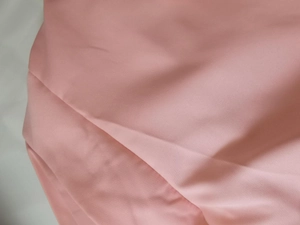 Vue détaillée montrant la texture satinée rose lisse et le tissu brillant du blazer