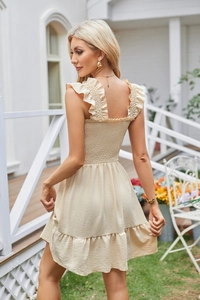 Detail of smocked elastic bodice and ruffled straps on apricot summer mini dress