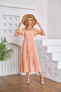 Detail of peach ruffled midi dress featuring tiered hem and shirred waist texture