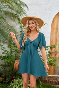 Detail of teal mini dress featuring V-neckline, bow tie front, and flutter sleeves