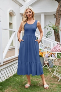 Outdoor shot showing details of the blue sleeveless dress with pockets and pleated hem