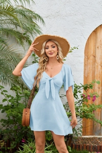 Detail of light blue mini dress with V-neck bow tie and textured fabric on model