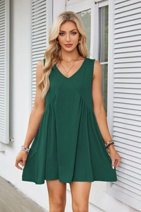 Close-up of deep green sleeveless V-neck dress featuring high-waisted pleated details