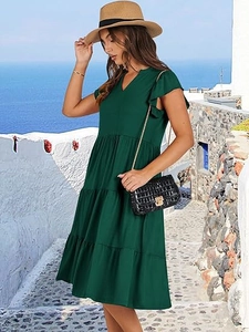 Detail of V-neck tiered dark green midi dress with ruffle sleeves in outdoor setting
