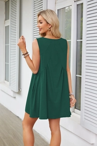 Detail view showing the deep green sleeveless dress with high waist and pleated A-line hem