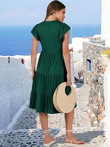 Detail shot of the deep green dress featuring layered tiered skirt and ruffled sleeve cuffs