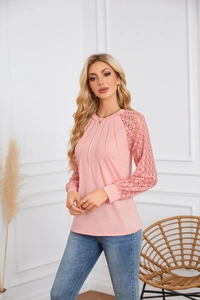 Close-up of pink long sleeve top featuring intricate lace patchwork on raglan sleeves