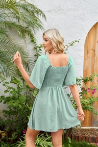 Detail of smocked elastic back and puff sleeves on this mint green V-neck mini dress