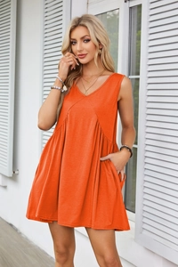 Detail of a bright orange sleeveless V-neck mini dress with pockets and pleated skirt