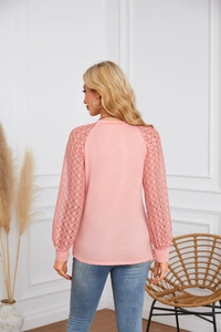 Detail of pink long sleeve top featuring intricate diamond lace hollow sleeves and crew neck