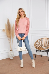 Detailed close-up of pink long-sleeve top with crochet lace sleeves and pleated neckline