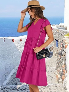 Detail of V-neck tiered magenta dress with ruffle sleeves in a scenic outdoor setting