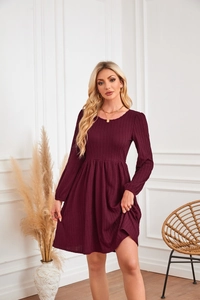 Gros plan sur la texture torsadée de la robe en maille bordeaux et les manches longues