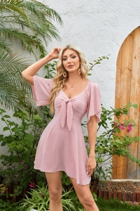 Detail of pink V-neck mini dress showing bow tie front and ruffled bell sleeves