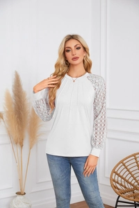 Detailed view of white pleated top with intricate lace sleeves and round neckline