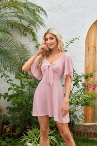 Detail of pink V-neck dress featuring bow-tie neck and ruffle short sleeves in summer garden
