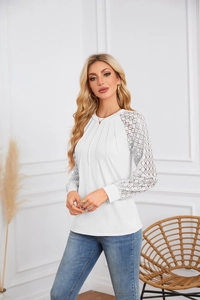 Detailed close-up of white long sleeve top with lace stitching and pleated crew neck