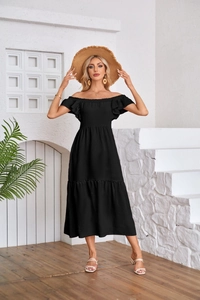 Detail of off-shoulder black dress with ruffled hem and smocked sleeves in summer sun