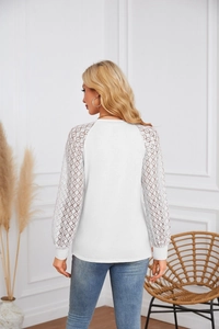 Detailed back view of white long sleeve top with intricate lace patchwork sleeves