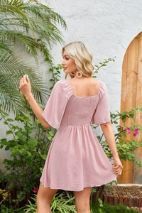 Detailed back view of a pink V-neck mini dress with shirred elastic waist and tie knot