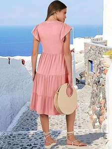 Pink V-neck tiered midi dress with ruffle sleeves and pockets, modeled at a coastal setting
