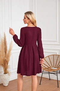 Détail de la robe en maille bordeaux avec motif torsadé, manches bouffantes et taille plissée