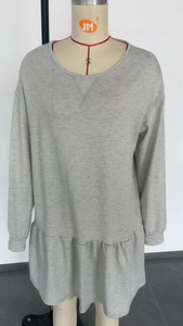 Detail of light grey long sleeve dress with criss-cross neckline and ruffled hem