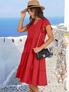 Detail view of red V-neck ruffle sleeve dress featuring tiered skirt in beach setting