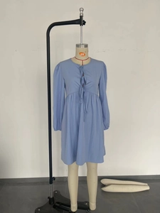 Dettaglio dell'abito a trapezio celeste con scollo rotondo e decorazioni a pieghe