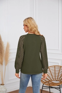 Detail view of lace patchwork sleeves with hollow geometric patterns on a green top
