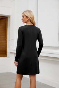 Detail view of the black long-sleeve mini dress featuring a side split and straight cut