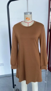Detail of a brown long-sleeved crewneck mini dress featuring a pleated back and side pockets