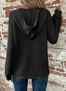 Detail of black waffle knit fabric texture on a long sleeve hoodie with a relaxed fit