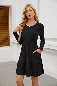 Detail of rib-knit black dress featuring practical side pockets and ruffled hemline