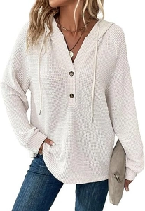 Detail of white waffle knit hoodie showing V-neckline with brown buttons and textured fabric