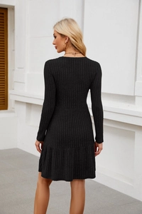 Detail of black ribbed knit long sleeve dress showing slim fit and pleated ruffle hemline