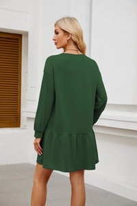 Detail of dark green long sleeve dress with ruffle hem and soft knitted fabric texture