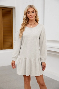 Detail of light grey knit dress featuring a ruffled hem and ribbed long sleeves